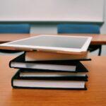 silver ipad on stack of books
