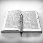 grayscale photography of click pen on top of opened book