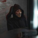person in black hoodie hacking a computer system